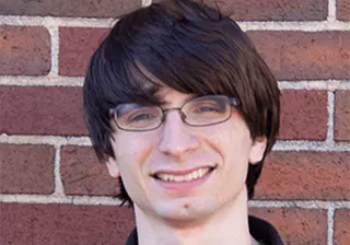 Kyle Kubik, Senior Engineer, smiling in front of a brick wall.