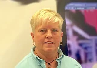Lisa Whitman, Operations Manager, smiling in a teal shirt.