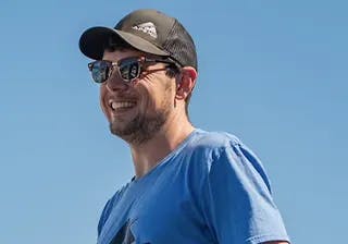 Andrew Rains smiling in Ray Bans at the race track.