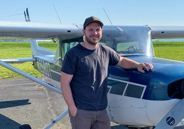 Bain Gurley, graphic designer and app developer, leaning against a Cessna plane.